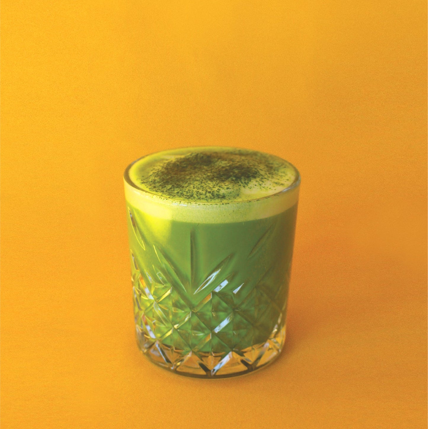 Decorative glass with matcha latte on an orange background