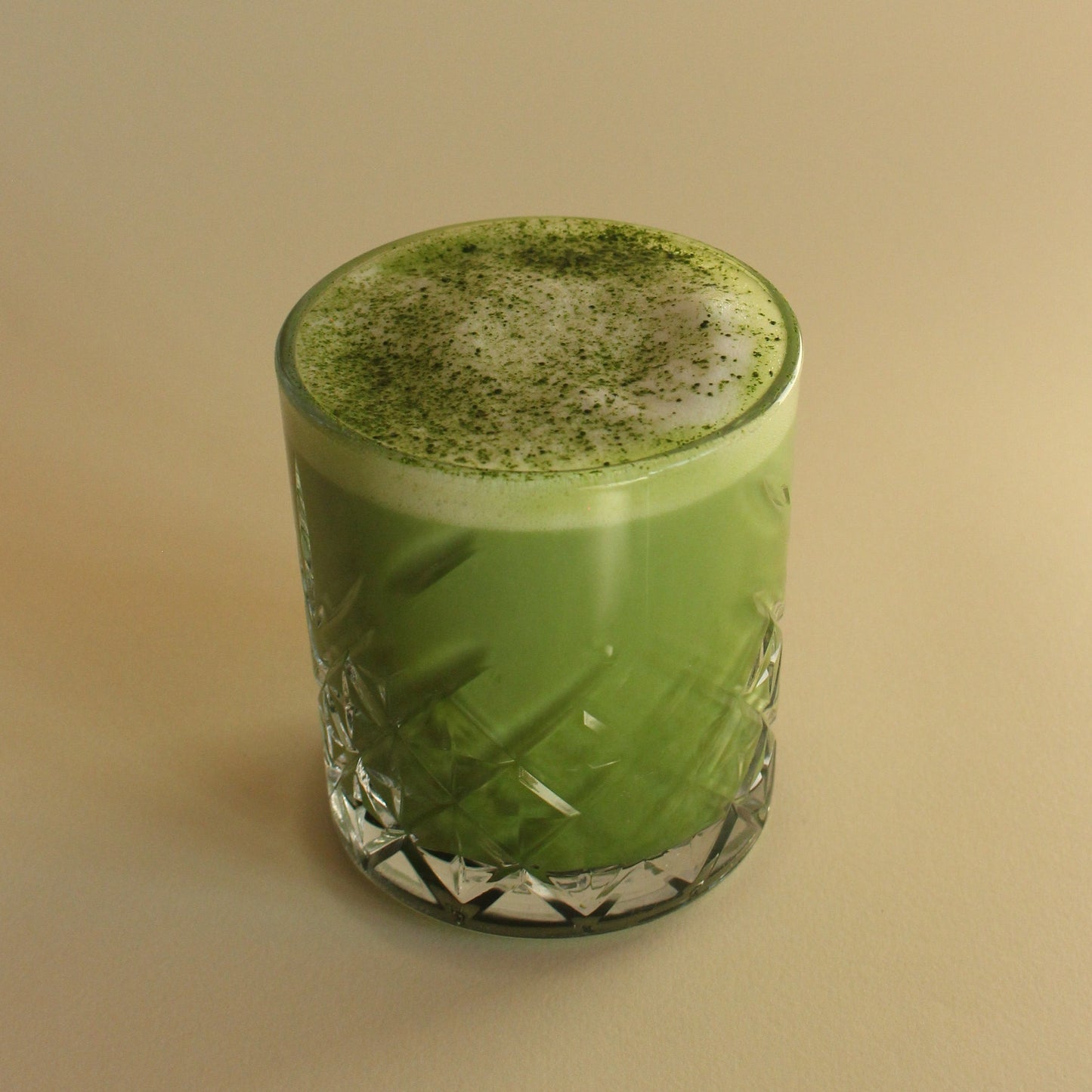 Matcha latte in a glass with a textured surface on a beige background