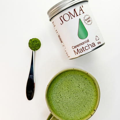 Soma Ceremonial Matcha with a spoonful of matcha powder on a white background