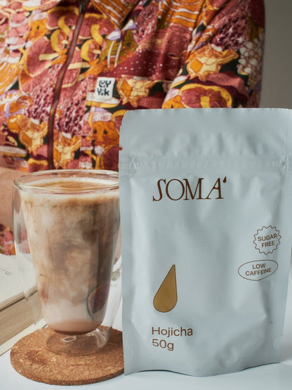 Soma Hojicha pouch with an iced hojicha latte in a glass on a cork coaster