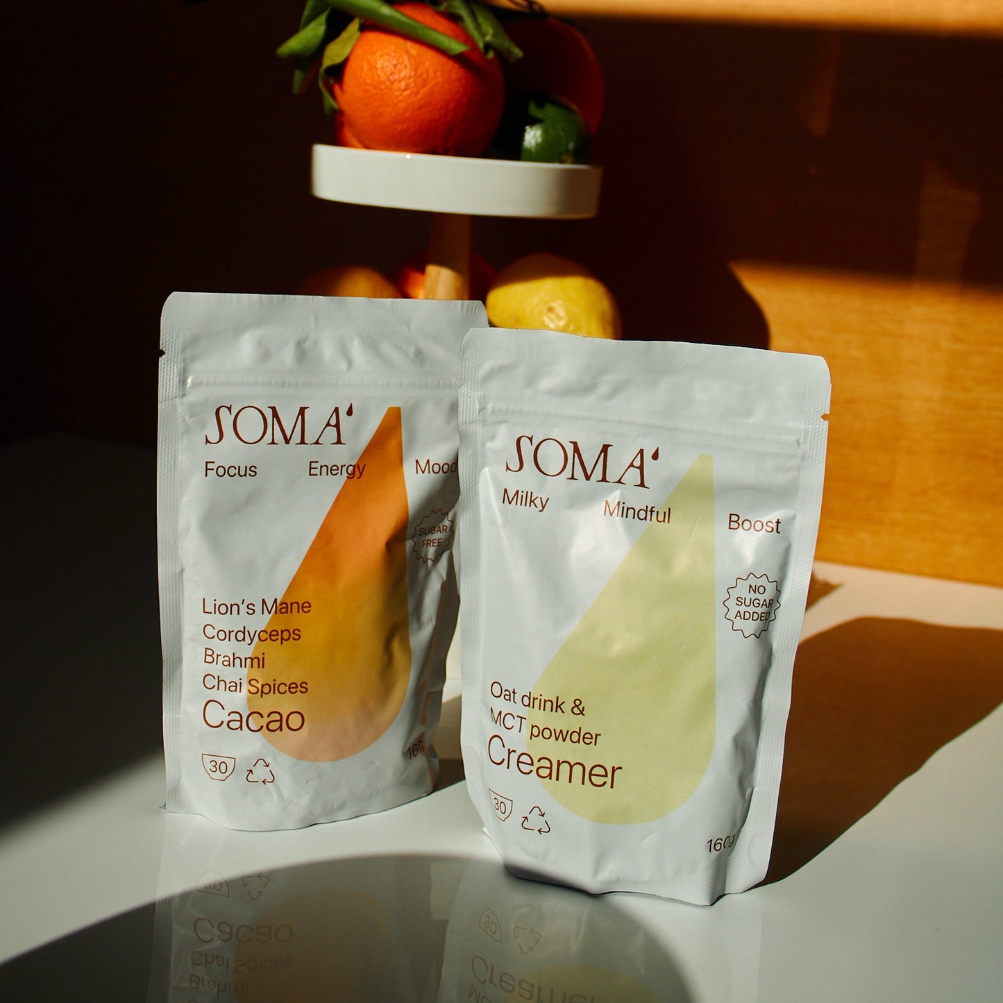 Two SOMA food packaging products on a reflective surface with a dark background
