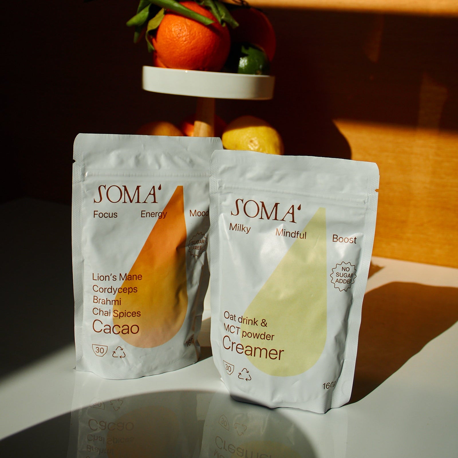 Two SOMA food packaging products on a reflective surface with a dark background